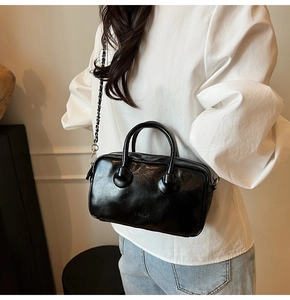Close-up of black glossy bowling bag with silver chain strap and dual top handles