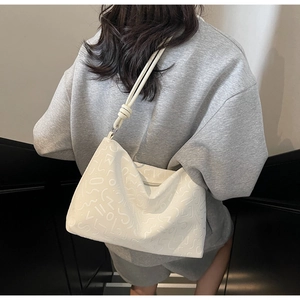 Détail du sac à bandoulière blanc avec gaufrage abstrait et bandoulière à nœuds élégante