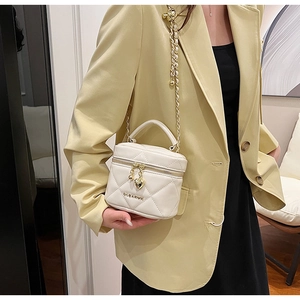 Détail du sac cylindre matelassé blanc avec chaîne dorée et pendentif cœur