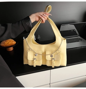 Close-up of cream leather tote with utility pockets and heart charms on a desk