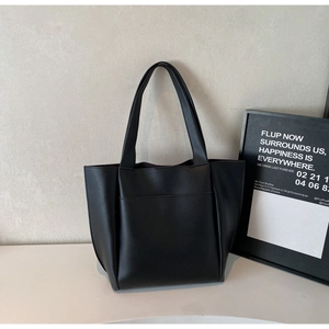 Detail shot of black matte PU leather tote bag with large front pocket and long straps