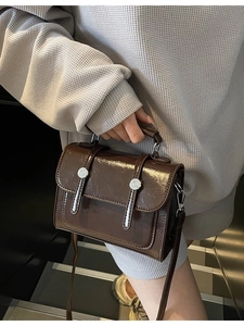 Sac bandoulière marron foncé brillant avec boucles argentées et poignée haute