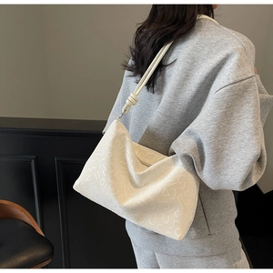 Détail du sac à bandoulière blanc avec texture gaufrée et bandoulière nouée sur modèle