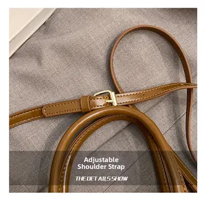 Detailansicht des verstellbaren Riemens mit Goldschnalle an brauner Handtasche
