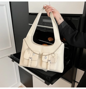 Detail of off-white multi-pocket tote bag with silver heart chain and buckle pockets