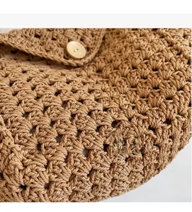 Detailed close-up of handmade woven texture and wooden button closure on a straw beach bag