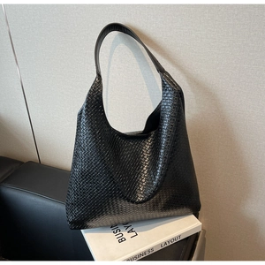 Detail of black woven leather hobo bag texture on a white book for casual commute