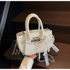 Detail of white bucket bag featuring lace bow, large pearls, and pebbled leather texture