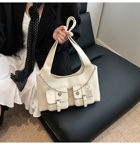Close-up of cream PU leather tote bag featuring dual flap pockets and silver heart chain