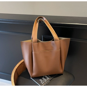 Detailed view of brown PU leather tote bag with front pocket on a black chair