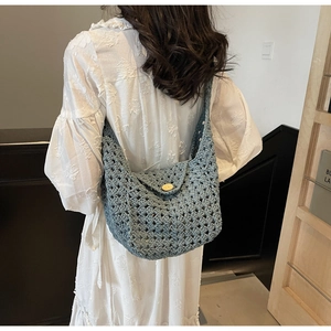 Close-up of blue crochet knit shoulder bag featuring hollow patterns and a wood button