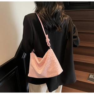 Détail d'un sac cabas rose clair avec textures gaufrées et bandoulière à nœuds