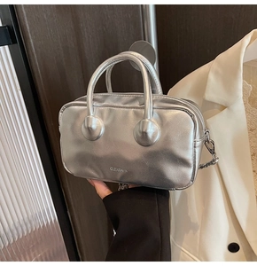 Detailed view of silver metallic Boston bag with dual handles and elegant chain strap