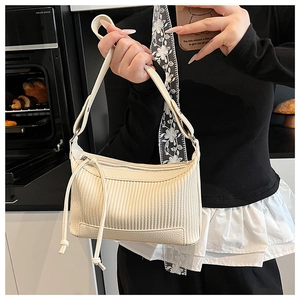 Vue détaillée du sac bandoulière crème avec texture gaufrée verticale et longs pompons