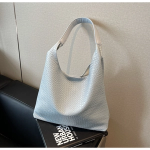 Detail shot of light blue woven hobo bag with signature cross texture and thick strap