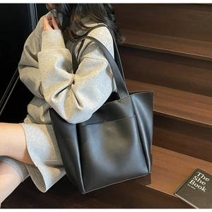 Detailed view of large black tote bag with outer pocket styled on wooden stairs