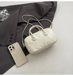 Close-up of off-white leather bowling bag with CLEAR UK text and chain strap