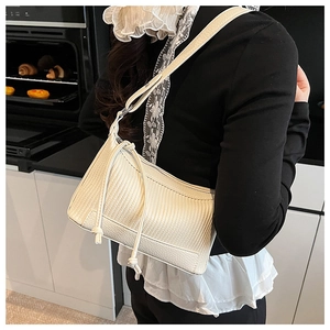 Détail du sac hobo en cuir beige à texture plissée porté par un mannequin femme