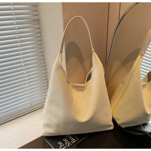 Detailed close-up of cream woven faux leather hobo tote bag texture and soft shoulder strap