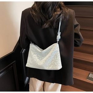 Sac bandoulière bleu clair à lignes abstraites blanches porté par un mannequin en blazer