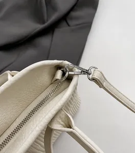 Nahaufnahme der silbernen Beschläge und des cremefarbenen Leders der Shopper-Tasche