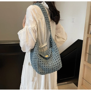 Close-up of gray-blue knit hollow crochet shoulder bag featuring a rustic wooden button