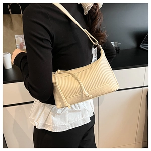 Détail du sac bandoulière en cuir plissé crème avec nœud latéral sur le mannequin