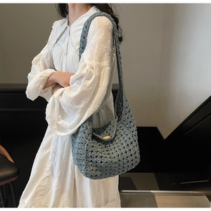 Detail of blue crochet knit bag with wooden button closure on white dress