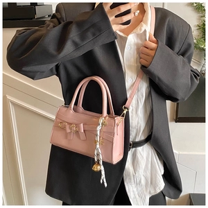Detail der rosa Lederhandtasche mit Schleife, Metallschnalle und gepunktetem Schal