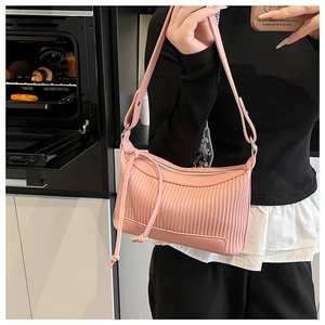 Sac à bandoulière rose plissé en cuir avec fermeture éclair à pompon en situation réelle