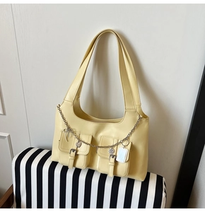 Detail of buttery yellow tote bag featuring utility buckle pockets and Y2K metal chains