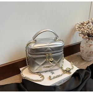 Détail du sac cylindre argenté matelassé avec zip cœur et bandoulière en chaîne