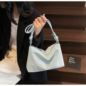 Détail du sac bandoulière bleu clair avec motifs abstraits et bandoulière à nœud décoratif