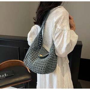 Detail of grey-blue hollow crochet bag showing intricate knit pattern and wooden button