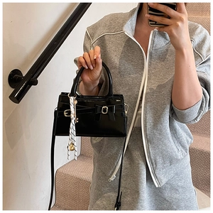 Detailansicht der schwarzen Lackledertasche mit Schleifendekor und modischem Seidenschal-Zubehör