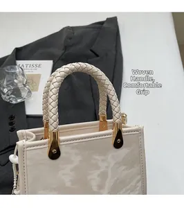 Detail showing the braided handle and golden hardware of the marble patterned handbag