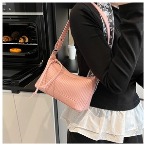 Détail du sac à bandoulière rose avec surpiqûres verticales et cordon de serrage en situation