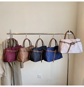 Detailed display of tote bags in five colors with brown leather handles and nylon texture