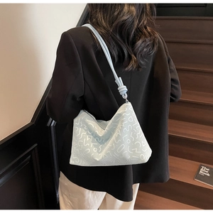 Détail du sac cabas bleu clair avec texture embossée et bandoulière à nœud élégante