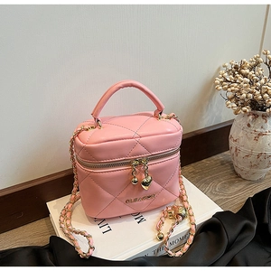 Détail du sac matelassé rose avec pendentifs cœur dorés et bandoulière chaîne dorée
