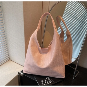 Detailed view of pink woven tote bag with wide shoulder strap in soft lighting