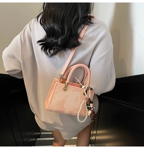 Detail of pink crossbody bag with braided handle, pearl chain and cute plush bear charm