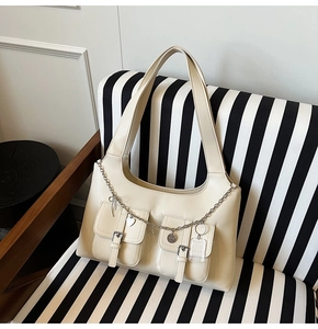 Close-up of cream PU leather tote bag featuring metal chains and heart pendants