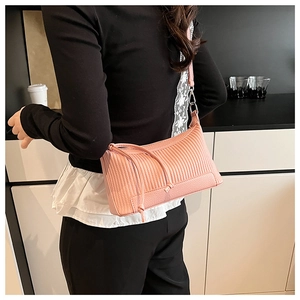 Sac sous le bras tendance en cuir rose froncé porté par un mannequin dans une cuisine
