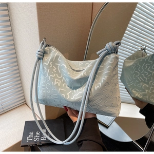 Détail du sac cabas bleu clair avec gaufrage graffiti blanc et lanières en cuir nouées