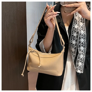 Détail du sac à bandoulière plissé beige avec nœud coulissant porté par le modèle