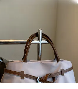 Detail of lavender nylon tote bag featuring brown leather handles and silver buckle strap
