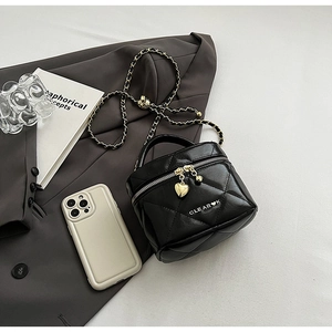 Détail d'un sac en cuir matelassé noir avec chaîne dorée et fermeture à glissière coeur