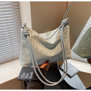 Détail du sac cabas bleu clair avec gaufrage de lettres et bandoulière à double nœud