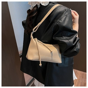 Détail du sac à bandoulière beige en cuir litchi avec nœuds décoratifs sur mannequin